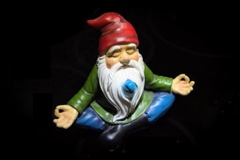 A meditating garden gnome wearing a red hat.